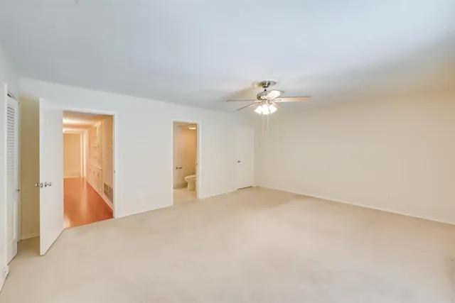a view of an empty room with chandelier fan