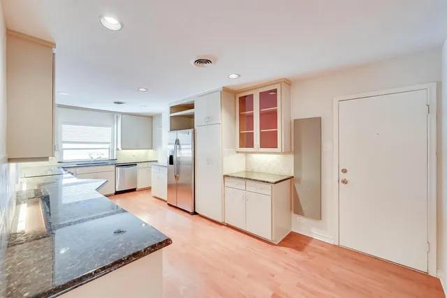 a kitchen with stainless steel appliances granite countertop a refrigerator sink and white cabinets