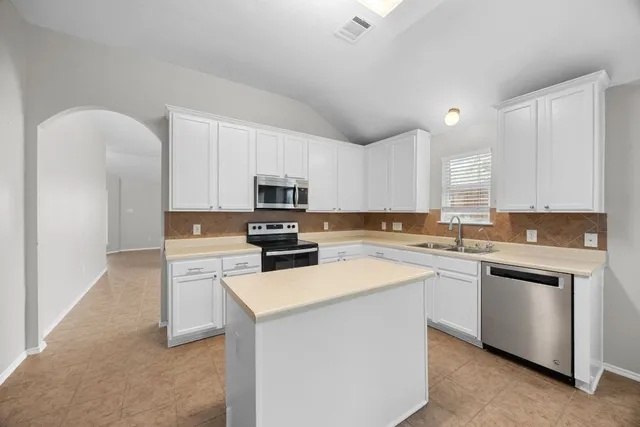 a kitchen with cabinets appliances a sink and a counter top space