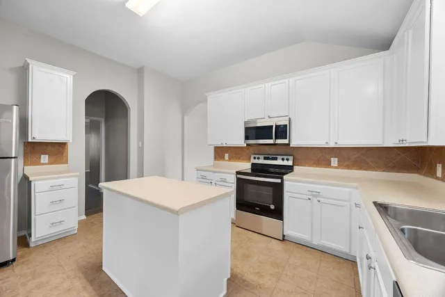 a kitchen with white cabinets and stainless steel appliances