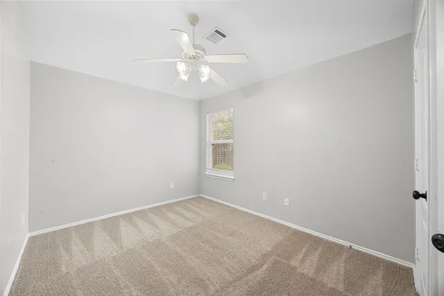 an empty room with a chandelier fan and windows
