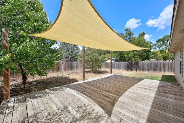a backyard of a house with table and chairs under an umbrella