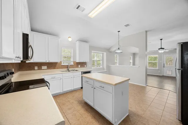 a large white kitchen with a sink and cabinets