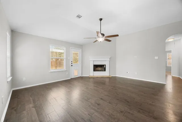 an empty room with wooden floor chandelier and windows