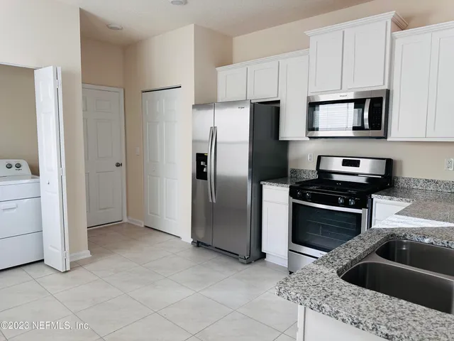 a kitchen with stainless steel appliances kitchen island granite countertop a refrigerator a stove and a sink