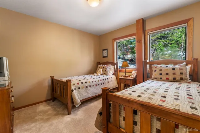 a bedroom with a bed a table and windows