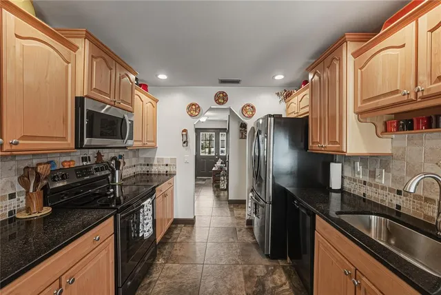 a kitchen with granite countertop a sink stainless steel appliances and cabinets