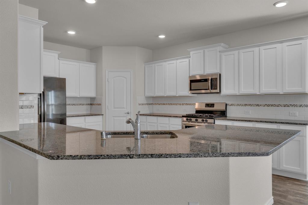 610 Bassett Hall Road Fate, TX 75189 - Photo 12 of 28 Kitchen with white cabinetry, sink, stainless steel appliances, and dark stone counters