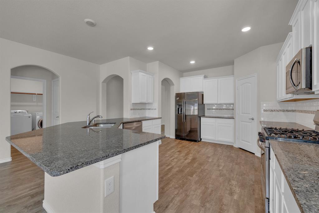 610 Bassett Hall Road Fate, TX 75189 - Photo 10 of 28 Kitchen featuring sink, separate washer and dryer, a center island with sink, appliances with stainless steel finishes, and white cabinets
