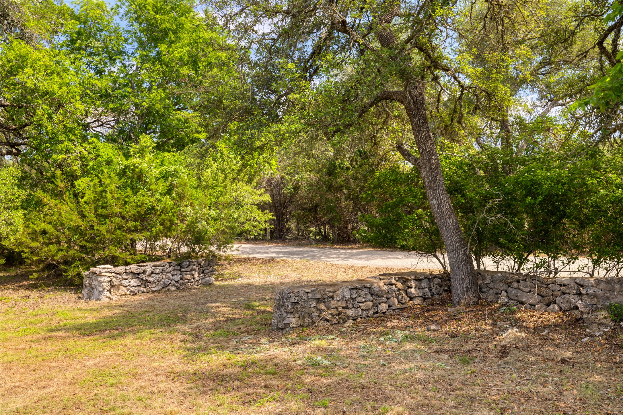 187 Beauchamp Road Dripping Springs, TX 78620 - Photo 8 of 19 Natural landscaping featuring mature trees and stone retaining walls