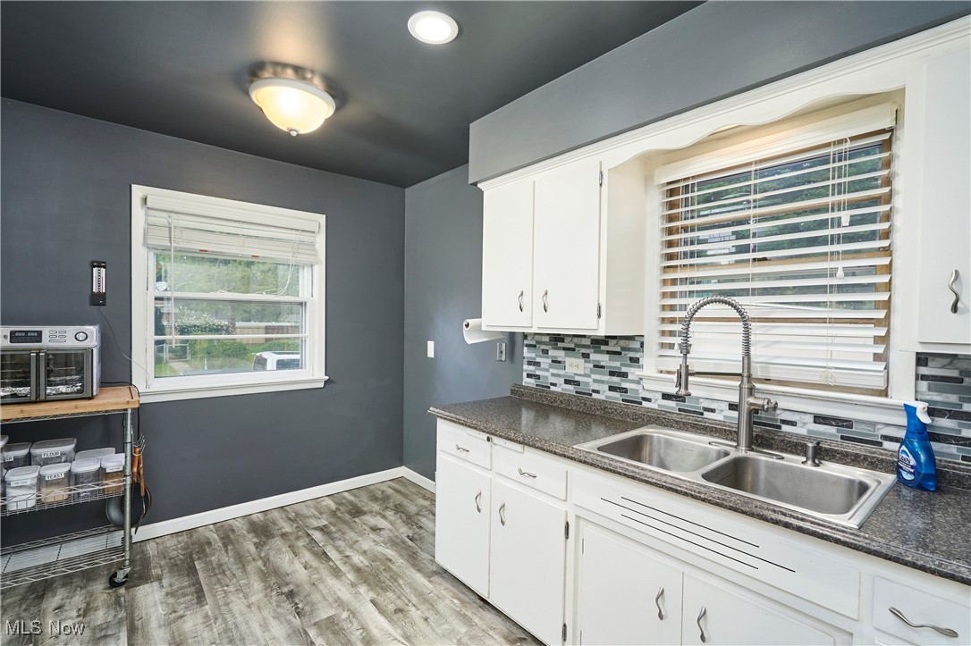 1129 Homestead Road Cleveland, OH 44121 - Photo 15 of 26 Kitchen featuring dark countertops, light wood-style flooring, white cabinetry, backsplash, and recessed lighting