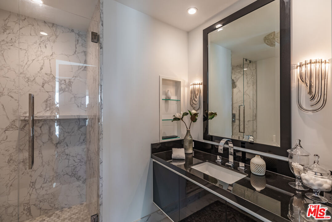 10727 Wilshire Boulevard, Unit 1702 Los Angeles, CA 90024 - Photo 21 of 43 a bathroom with a granite countertop sink and a mirror