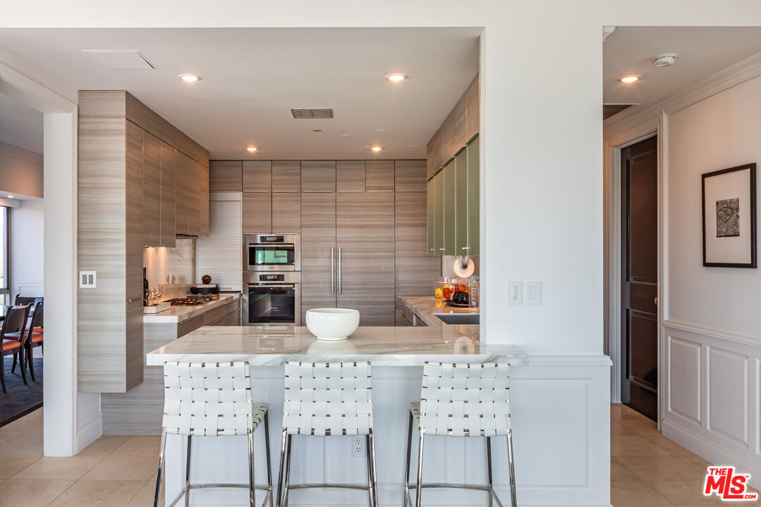 10727 Wilshire Boulevard, Unit 1702 Los Angeles, CA 90024 - Photo 8 of 43 a kitchen with stainless steel appliances kitchen island granite countertop a sink and cabinets