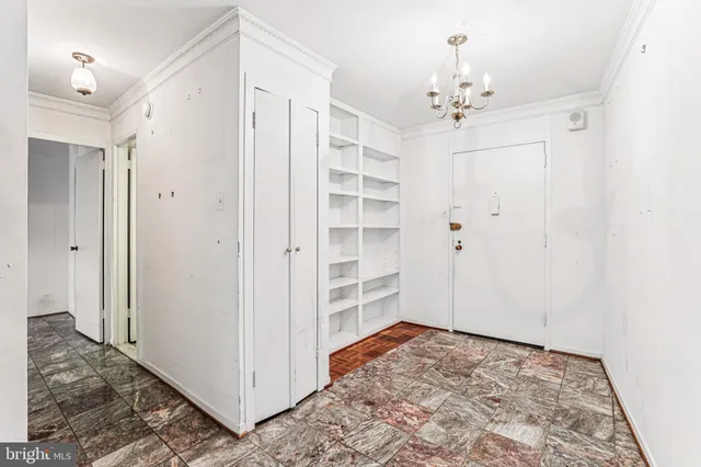 a view of a hallway with closet and chandelier fan
