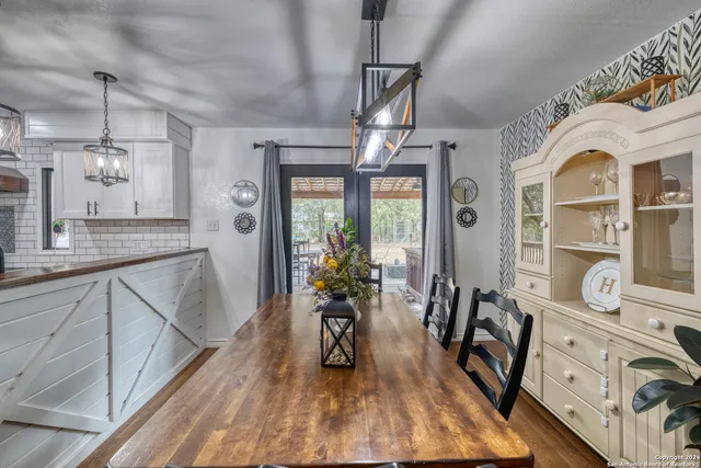 a dining room with wooden floor a chandelier a wooden table and chairs