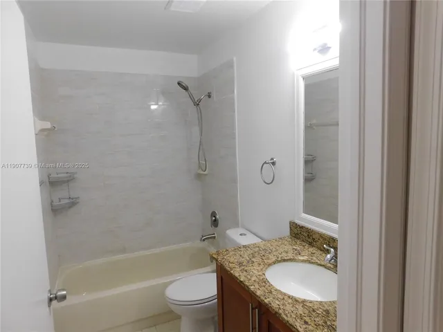 a bathroom with a granite countertop sink toilet tub and shower