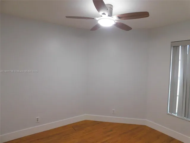 an empty room with a window and ceiling fan