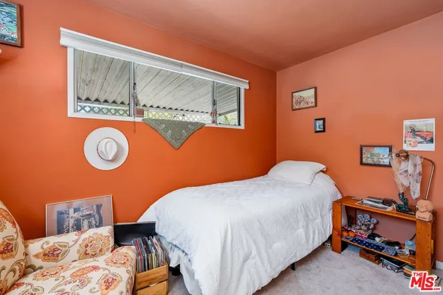 a bedroom with a bed and a lamp on dresser