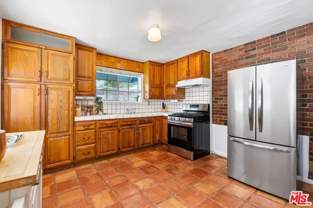 a kitchen with granite countertop a refrigerator a sink dishwasher a stove and white cabinets with wooden floor