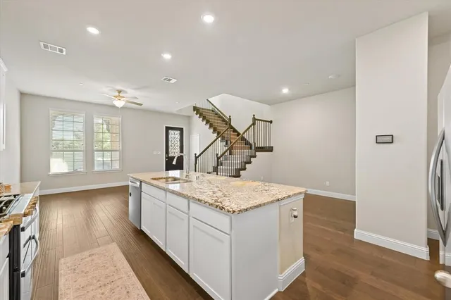 a large kitchen with stainless steel appliances granite countertop a sink stove and cabinets