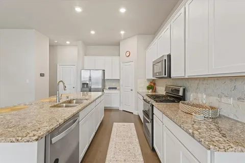 a large kitchen with stainless steel appliances granite countertop a sink stove and cabinets