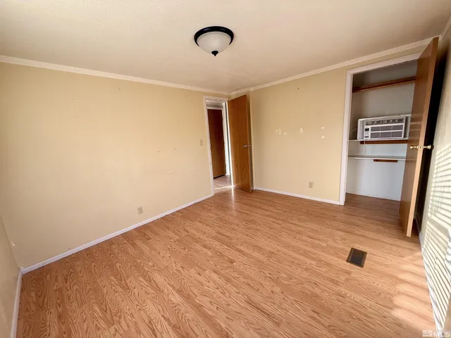 a view of a refrigerator in kitchen and an empty room with wooden floor