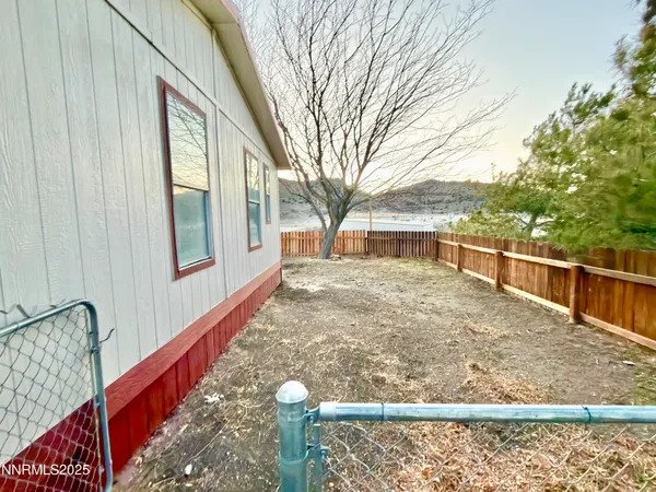 a view of balcony with two large trees and wooden fence