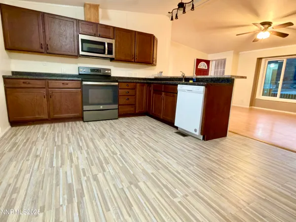 a kitchen with stainless steel appliances granite countertop a table chairs a sink and dishwasher a refrigerator with wooden floor