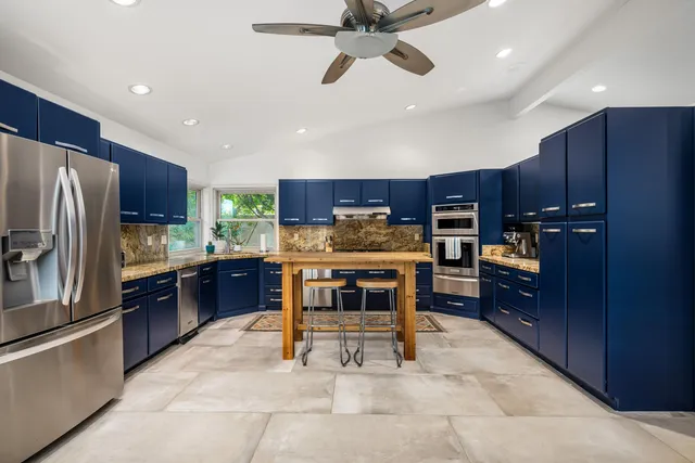 a kitchen with kitchen island granite countertop wooden cabinets and stainless steel appliances