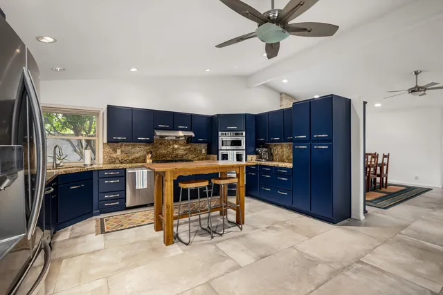 a kitchen with stainless steel appliances kitchen island granite countertop a refrigerator and a sink