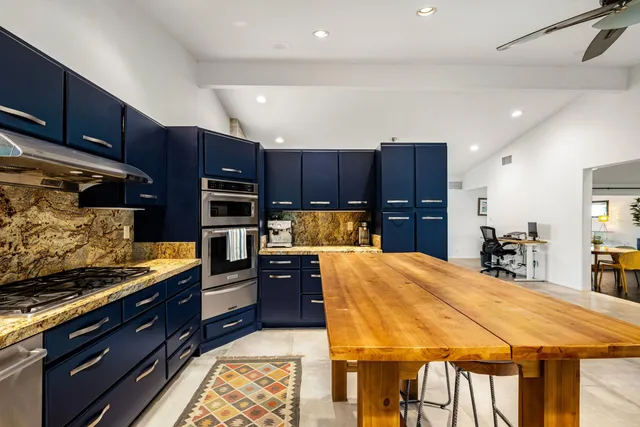 a kitchen with stainless steel appliances kitchen island granite countertop a refrigerator and a stove top oven