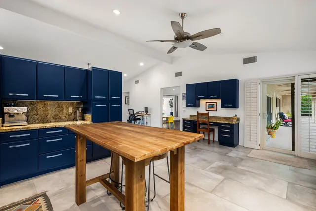 a kitchen with stainless steel appliances kitchen island granite countertop a table chairs sink and cabinets