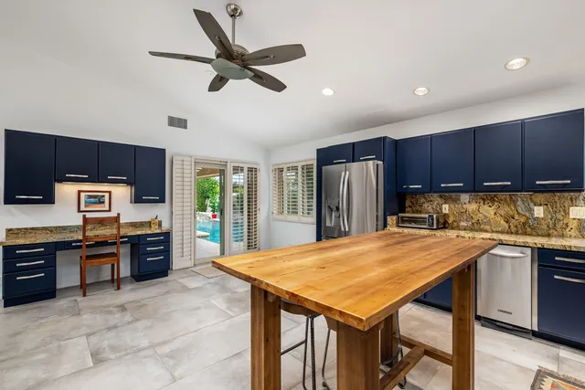 a kitchen with stainless steel appliances granite countertop a refrigerator a stove top oven a sink dishwasher and wooden cabinets with wooden floor