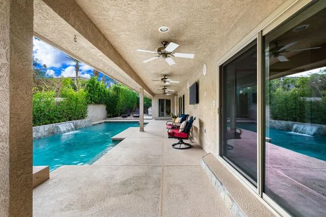 a view of a patio with table and chairs potted plants with floor to ceiling window