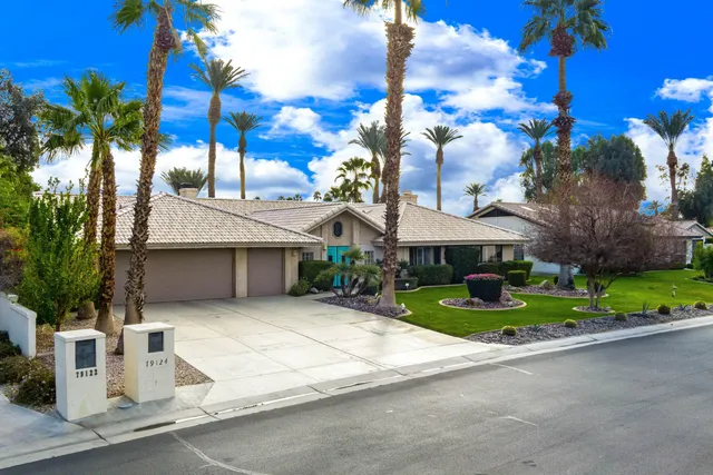 a front view of a house with a yard and potted plants