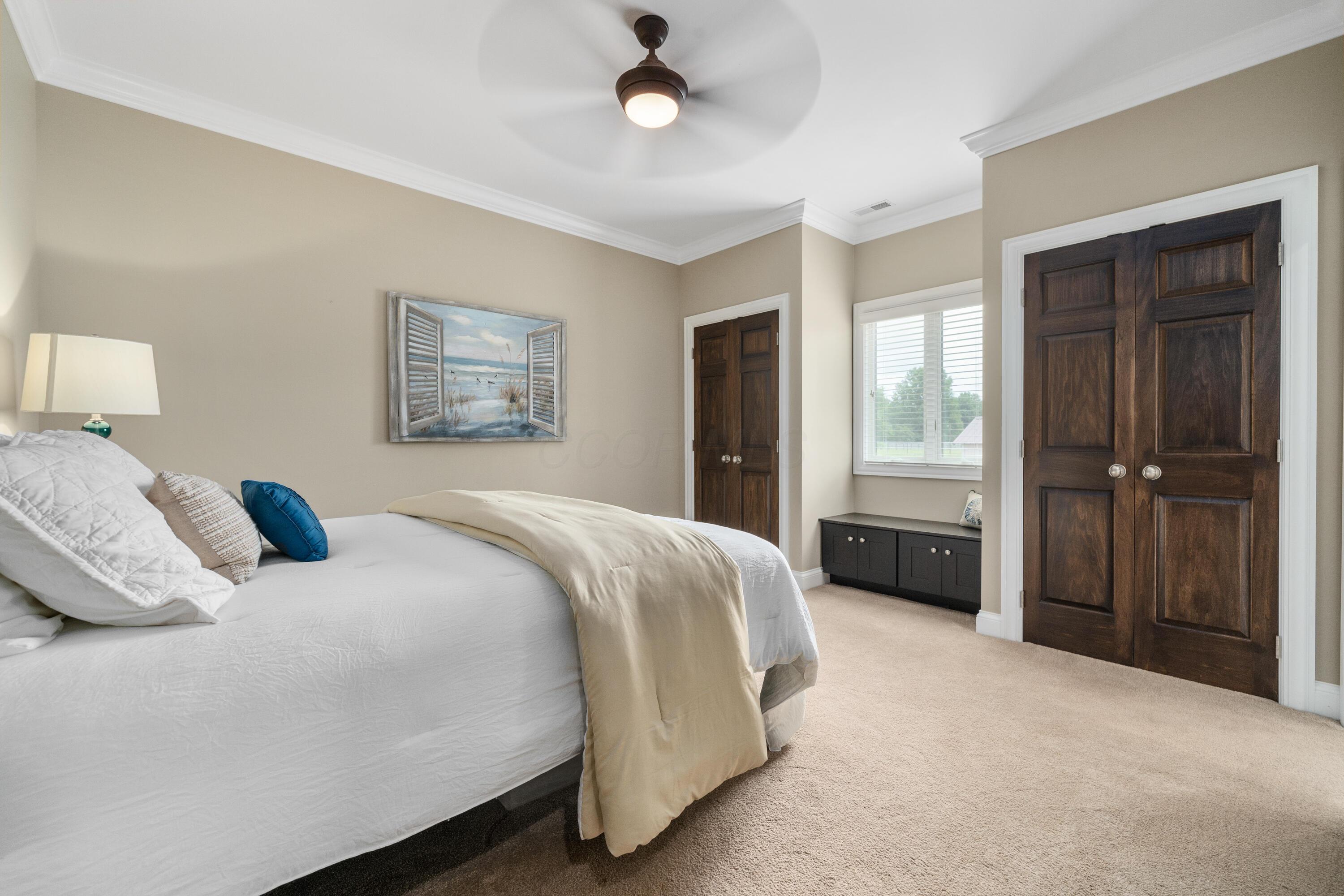 4640 Maynard Road Delaware, OH 43015 - Photo 45 of 91 Carpeted bedroom featuring a ceiling fan with integrated lighting, crown molding, and two dark wood panel doors