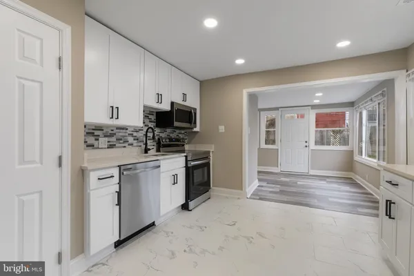 a kitchen with white cabinets and appliances