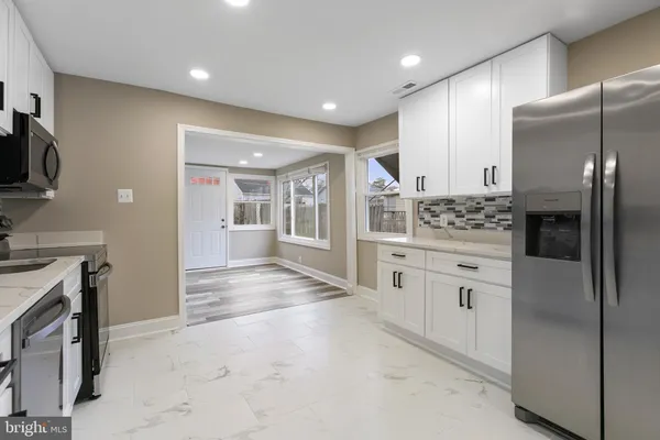 a kitchen with stainless steel appliances kitchen island granite countertop a refrigerator and a stove top oven