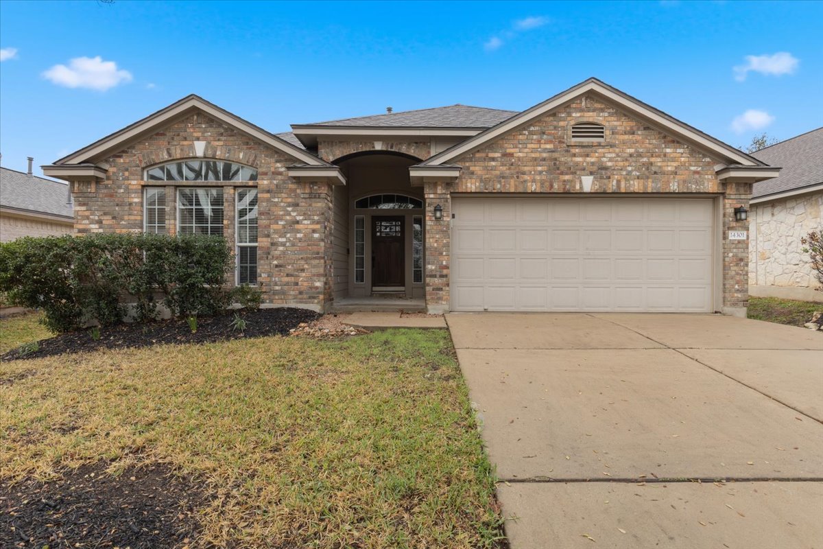 View of front of house featuring a garage, concrete driveway, a front lawn, brick siding, and a shingled roof
