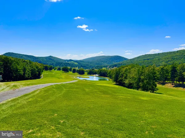 a view of a green field with mountains in the background