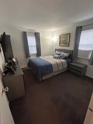 a spacious bedroom with a bed a couch and a dresser next to a window