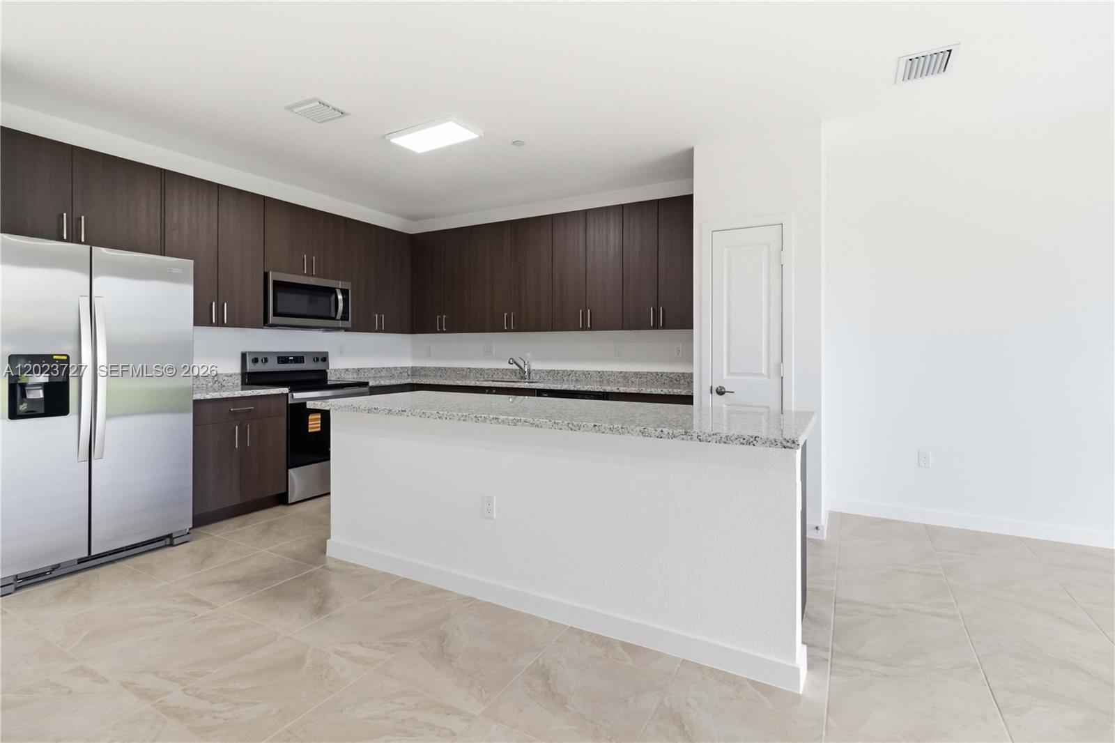 22348 Southwest 115th Court, Unit 22348 Miami, FL 33170 - Photo 8 of 37 a kitchen with granite countertop a refrigerator and a stove