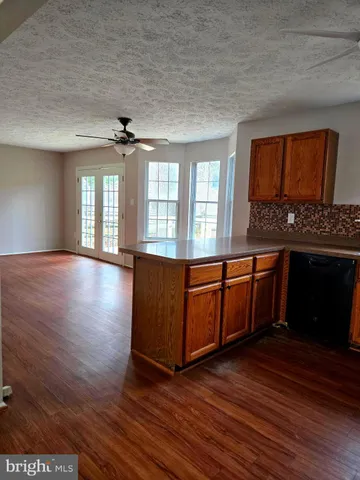 a living room with hard wood floors and a kitchen