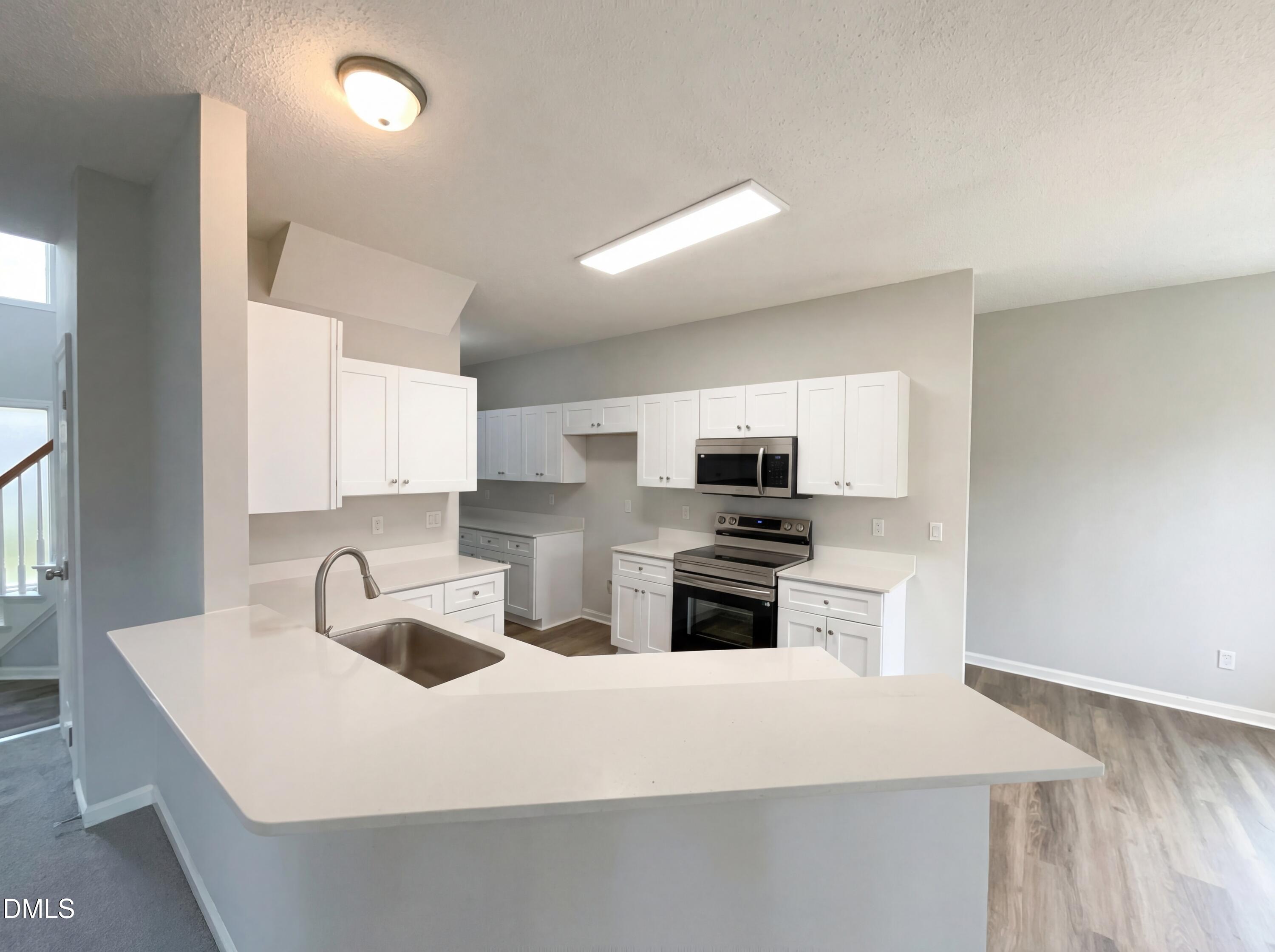 12213 Freemont Lane Raleigh, NC 27613 - Photo 18 of 19 a kitchen with stainless steel appliances a sink a stove a microwave a sink a refrigerator and cabinets