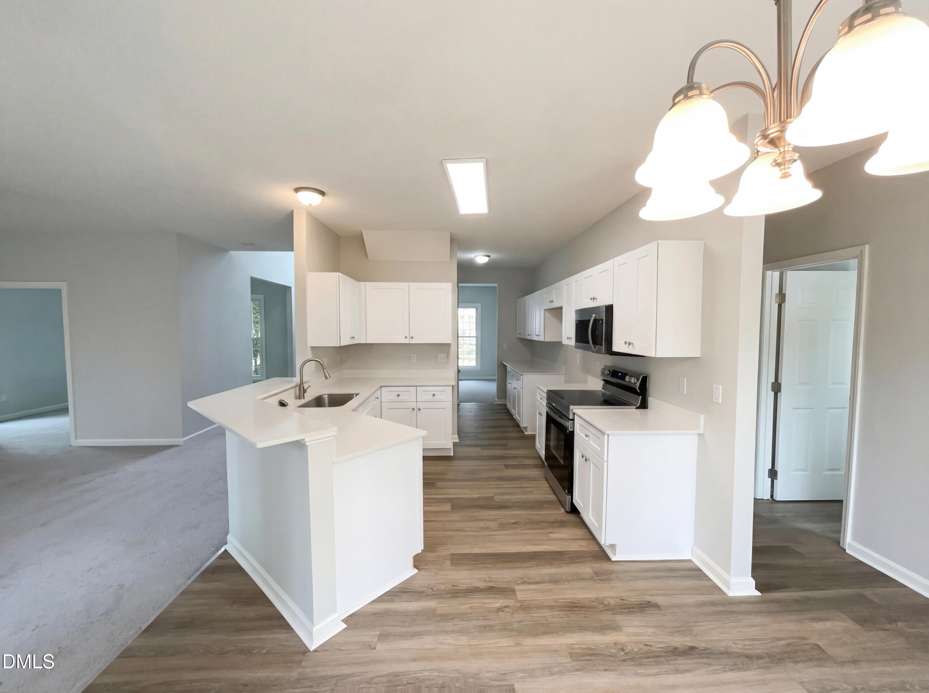 12213 Freemont Lane Raleigh, NC 27613 - Photo 2 of 19 a view of a kitchen with kitchen island a sink stainless steel appliances and cabinets