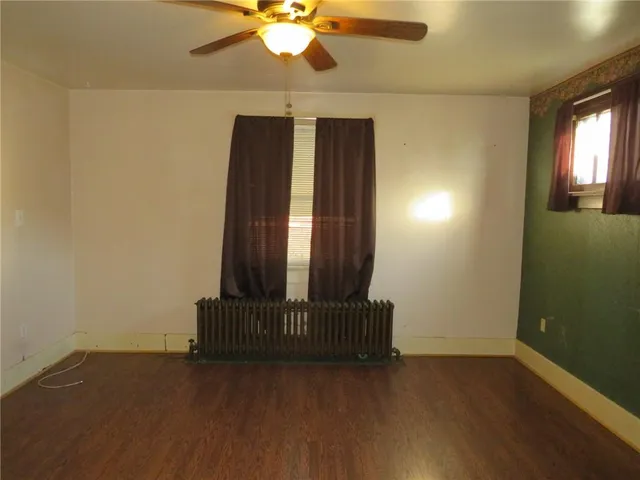 an empty room with wooden floor and fan
