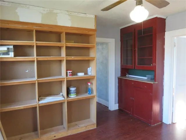 a view of a hallway to an empty room with wooden floor and a window