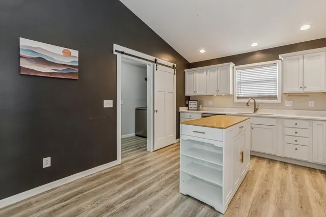a kitchen with a refrigerator stove and white cabinets with wooden floor