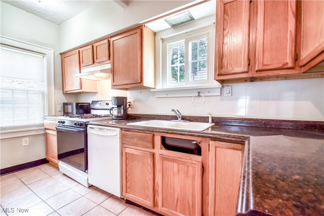 3733 East Antisdale Road Cleveland, OH 44118 - Photo 11 of 28 Kitchen featuring white appliances, light tile patterned floors, under cabinet range hood, a sink, and dark countertops