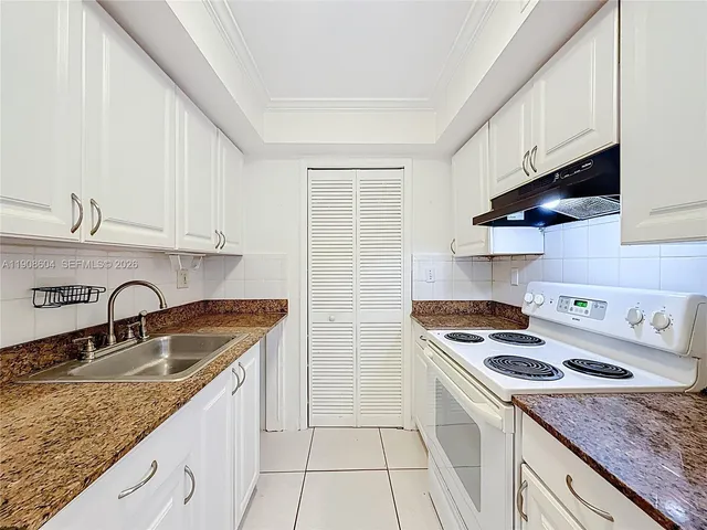 a kitchen with granite countertop a sink a stove and cabinets